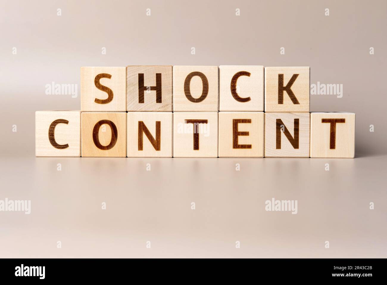 The word SHOCK CONTENT on wooden cubes on a beige neutral studio background. Copy Space. Written. Text words matter. Content manager occupation and Cr Stock Photo