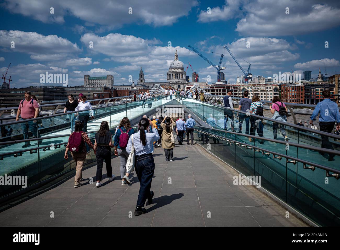 Millennium Bridge London - Tourists and commuters cross the Millennium Bridge between St Pauls Cathedral and the Tate Modern Art Gallery. Stock Photo