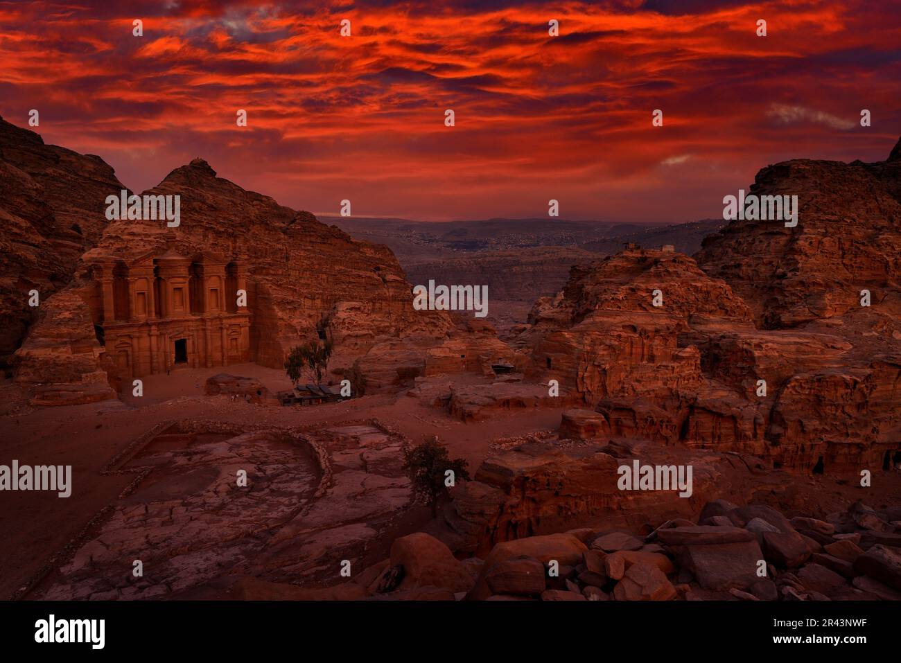 Stone Monastery in rock, Petra in Jordan. Red rock landcape. Petra historical sight - Ad Deir Monastery with full moon during the night. Evening light Stock Photo
