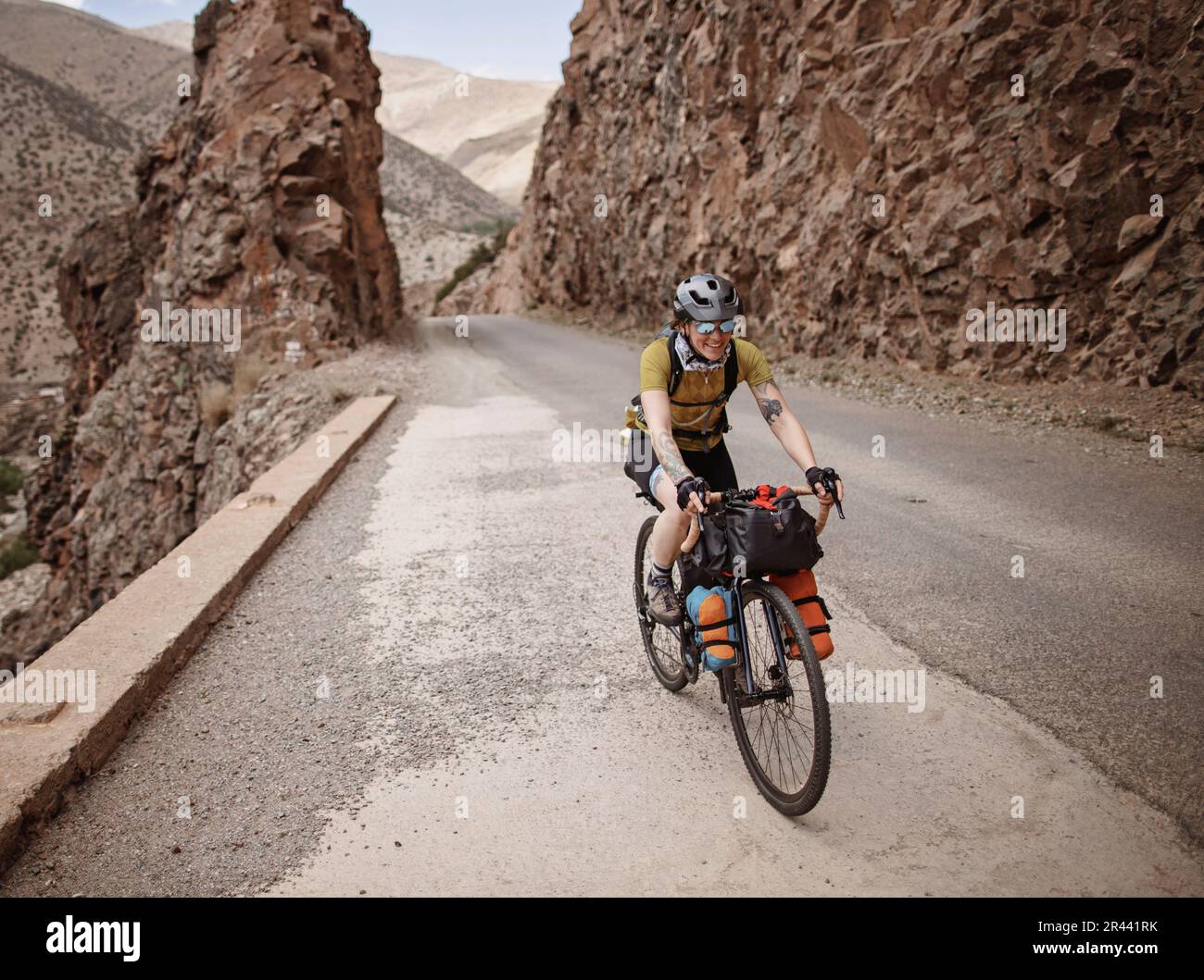 A female bike packer rides along a mountain road in the Atlas Mountain ...