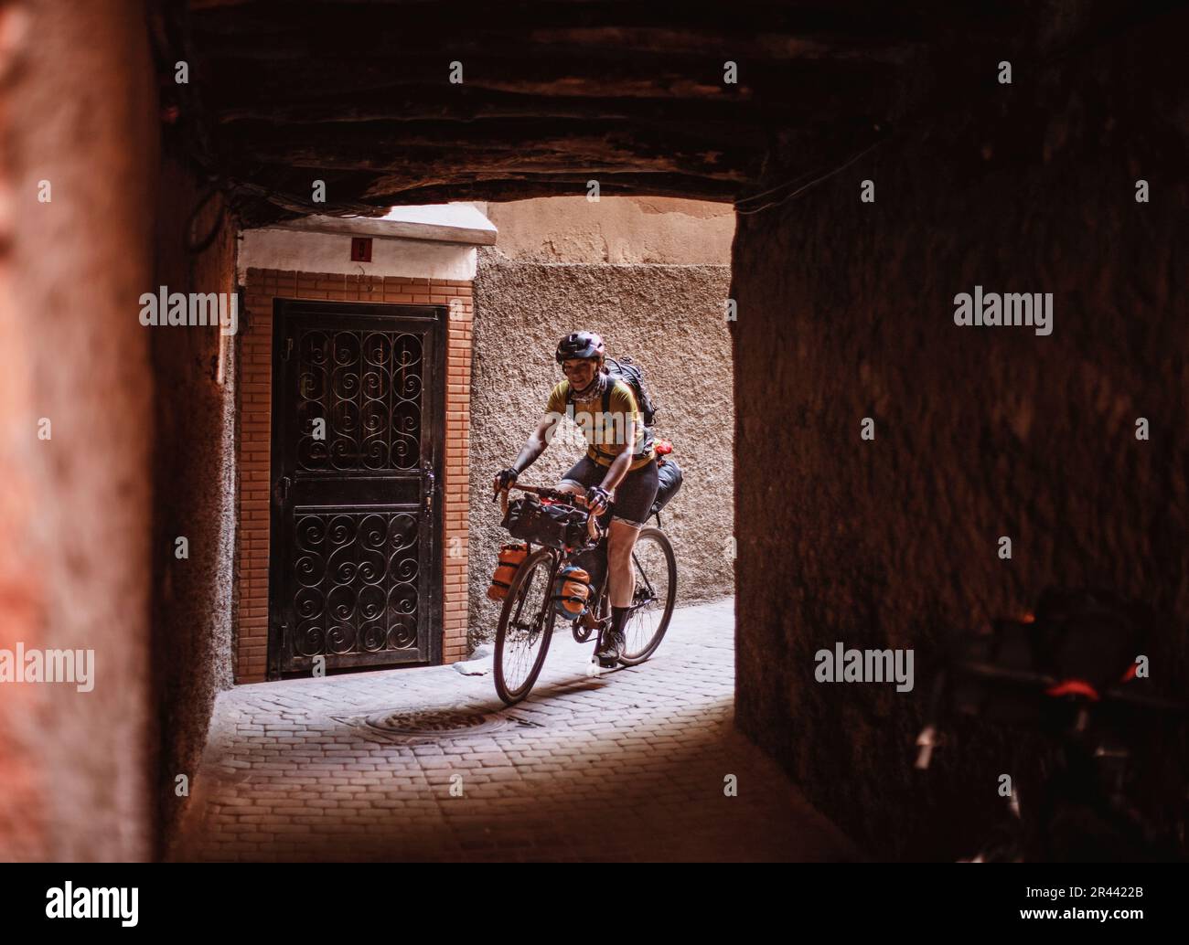 A female cyclist rides through a tunnel in the medina, Marrakesh Stock Photo