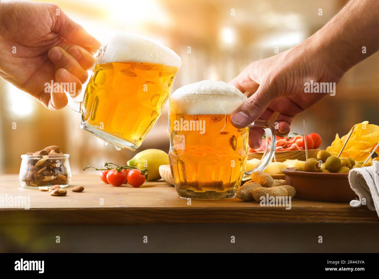 Partying friends having some beers with an appetizer on wooden bench at a bar counter. Front view. Stock Photo