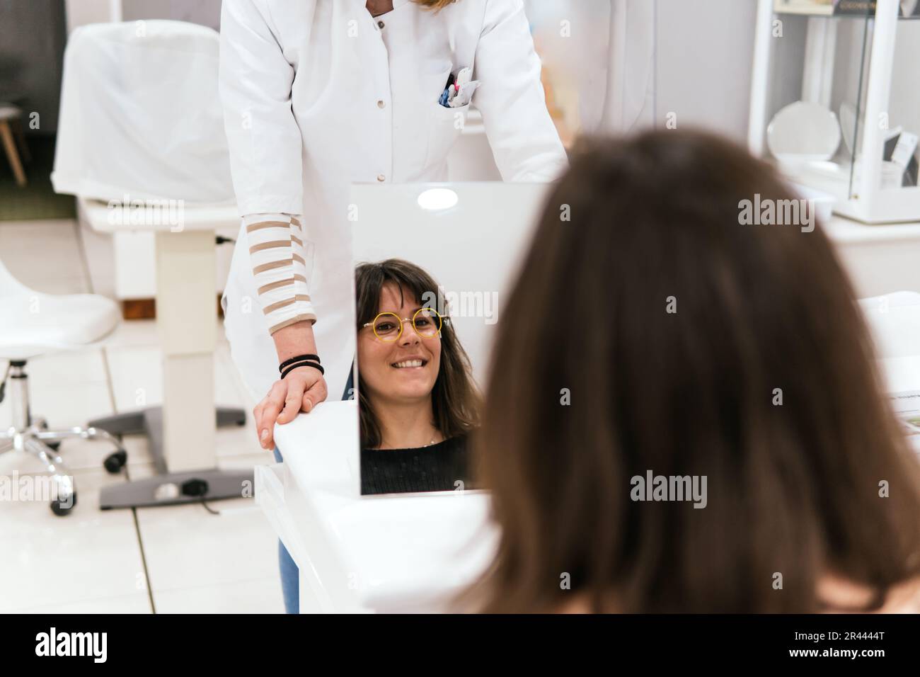 woman looking in the mirror while trying on glasses in an vision store Stock Photo