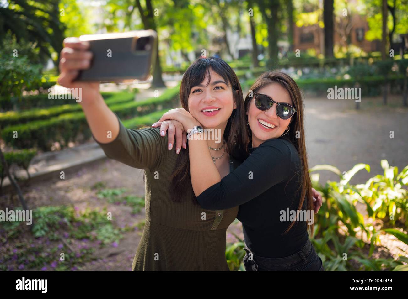 Two young latin female friends walking at the woods Stock Photo