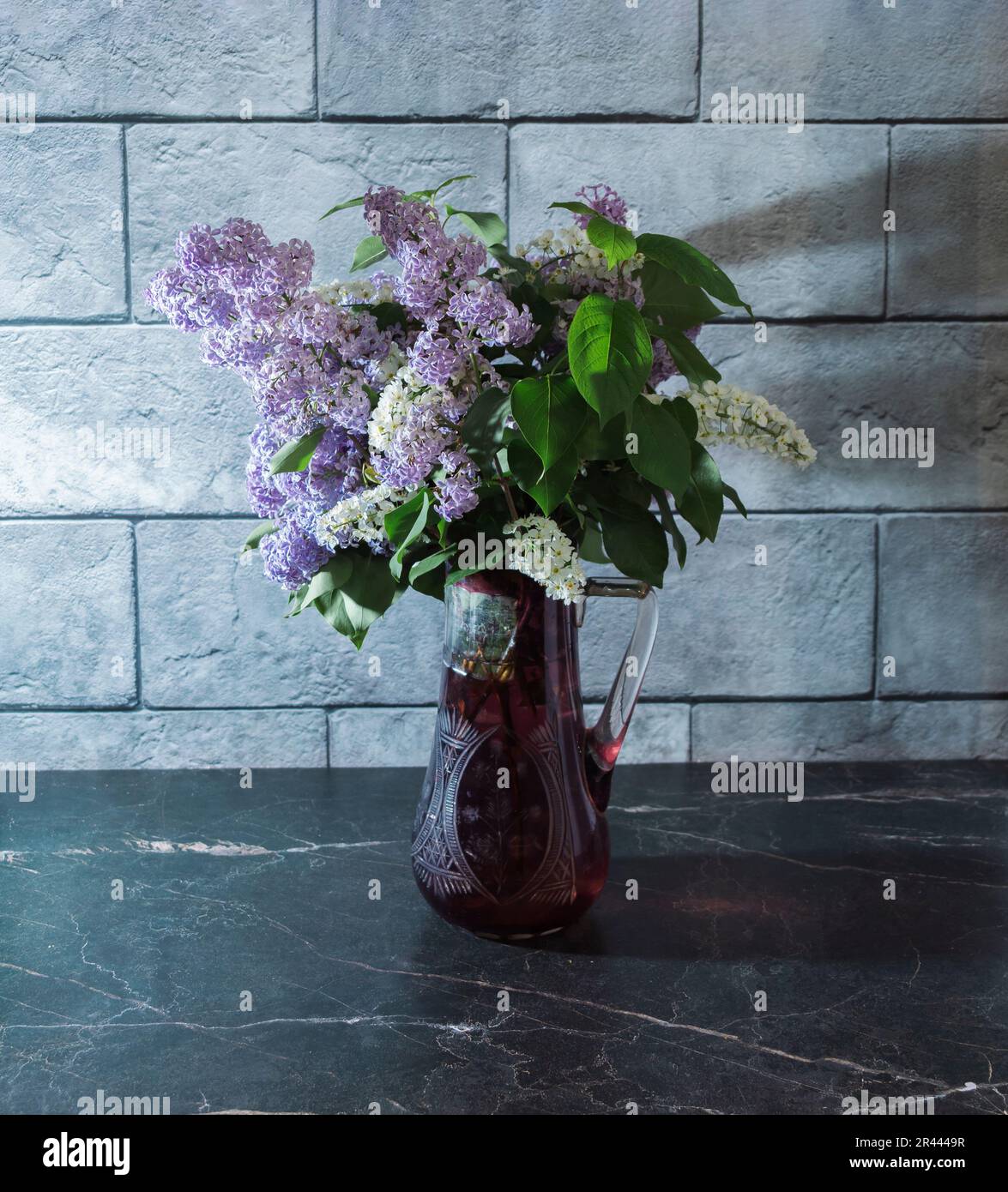 Still life with lilacs in a glass vase on a dark marble table. Concept ...