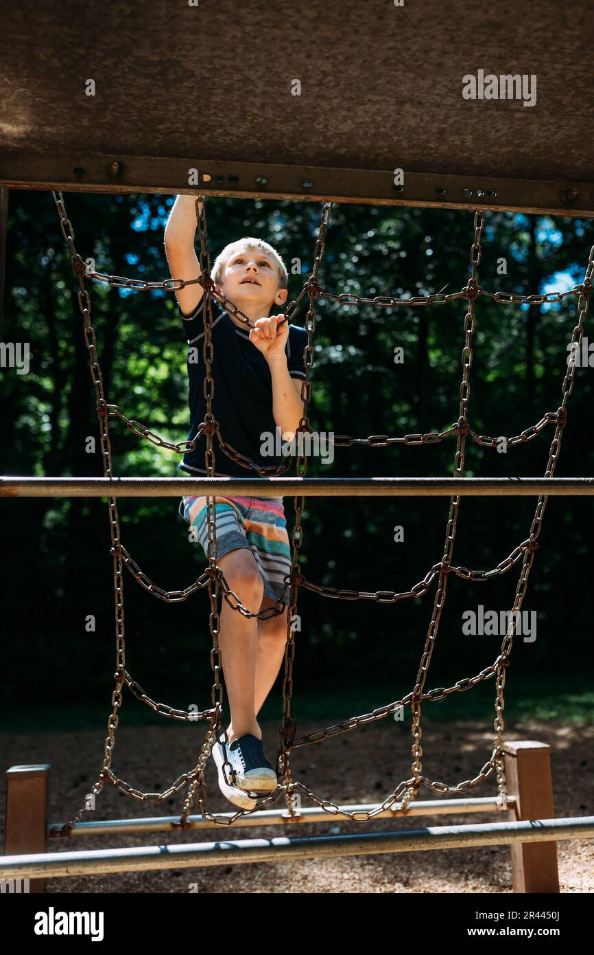 Child climbing on metal playground epuipment at park during summ Stock Photo