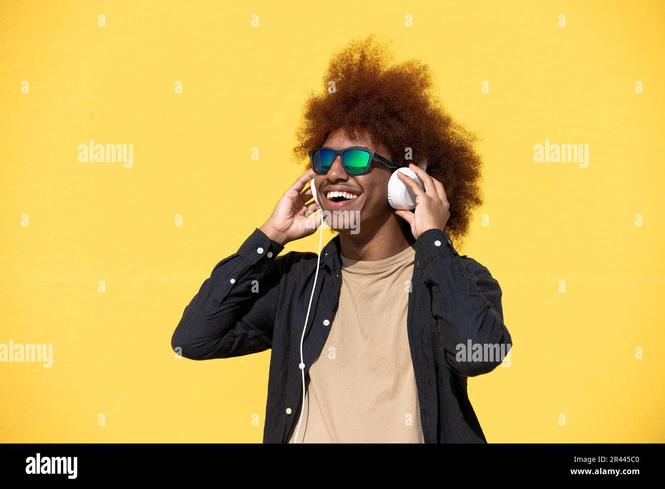 Cheerful young man wearing sunglasses and headphones having fun Stock Photo