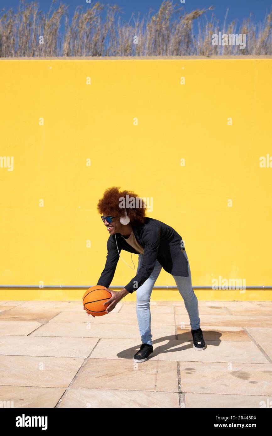 Young cheerful man playing basketball wearing sunglasses Stock Photo