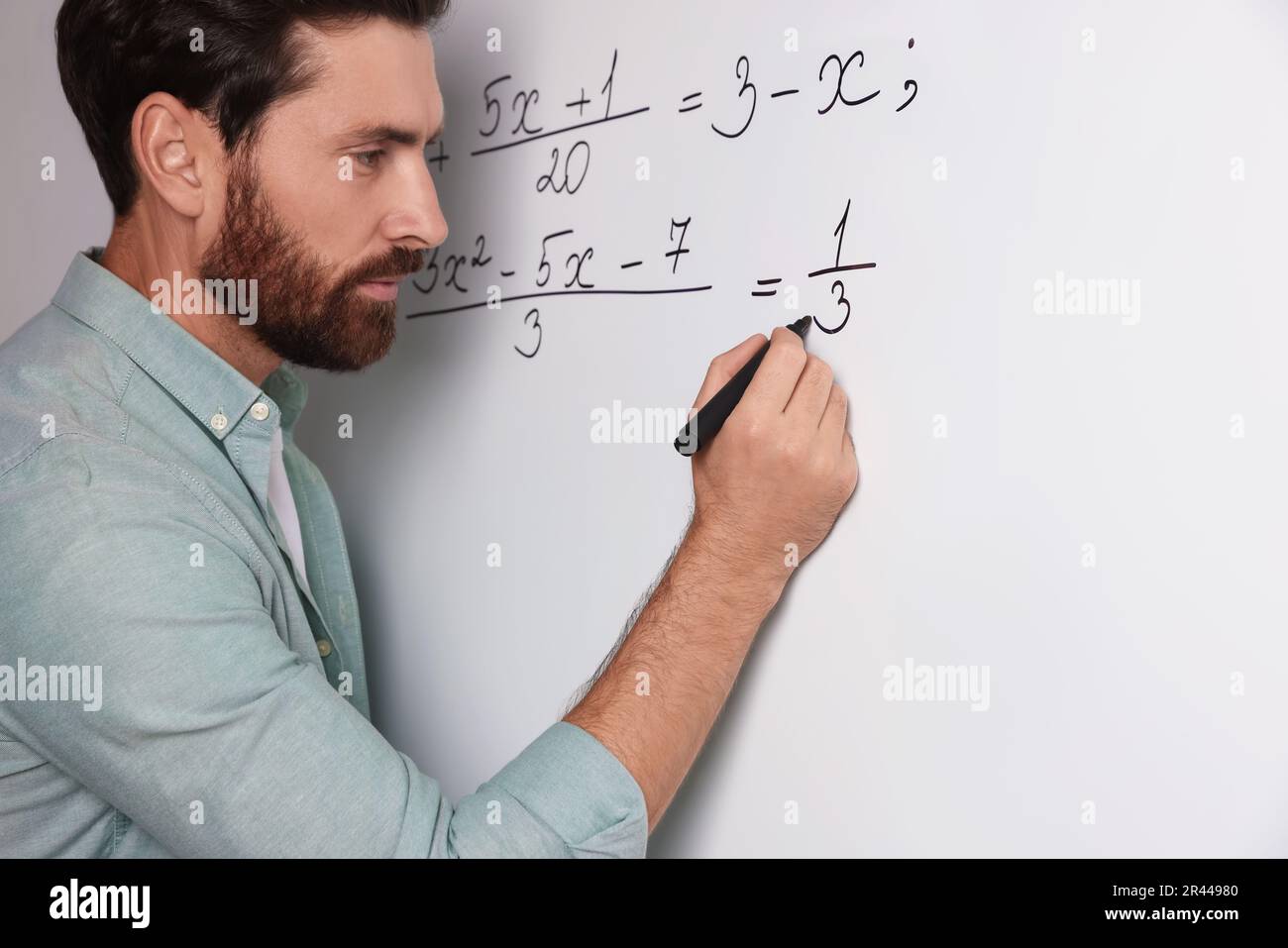 Mature teacher explaining mathematics at whiteboard in classroom ...