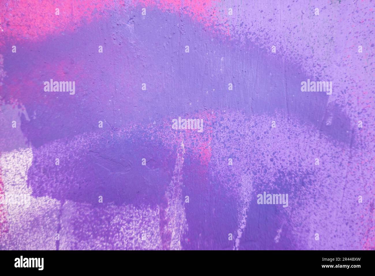 Purple paint strokes and smudges on an pink painted wall background ...