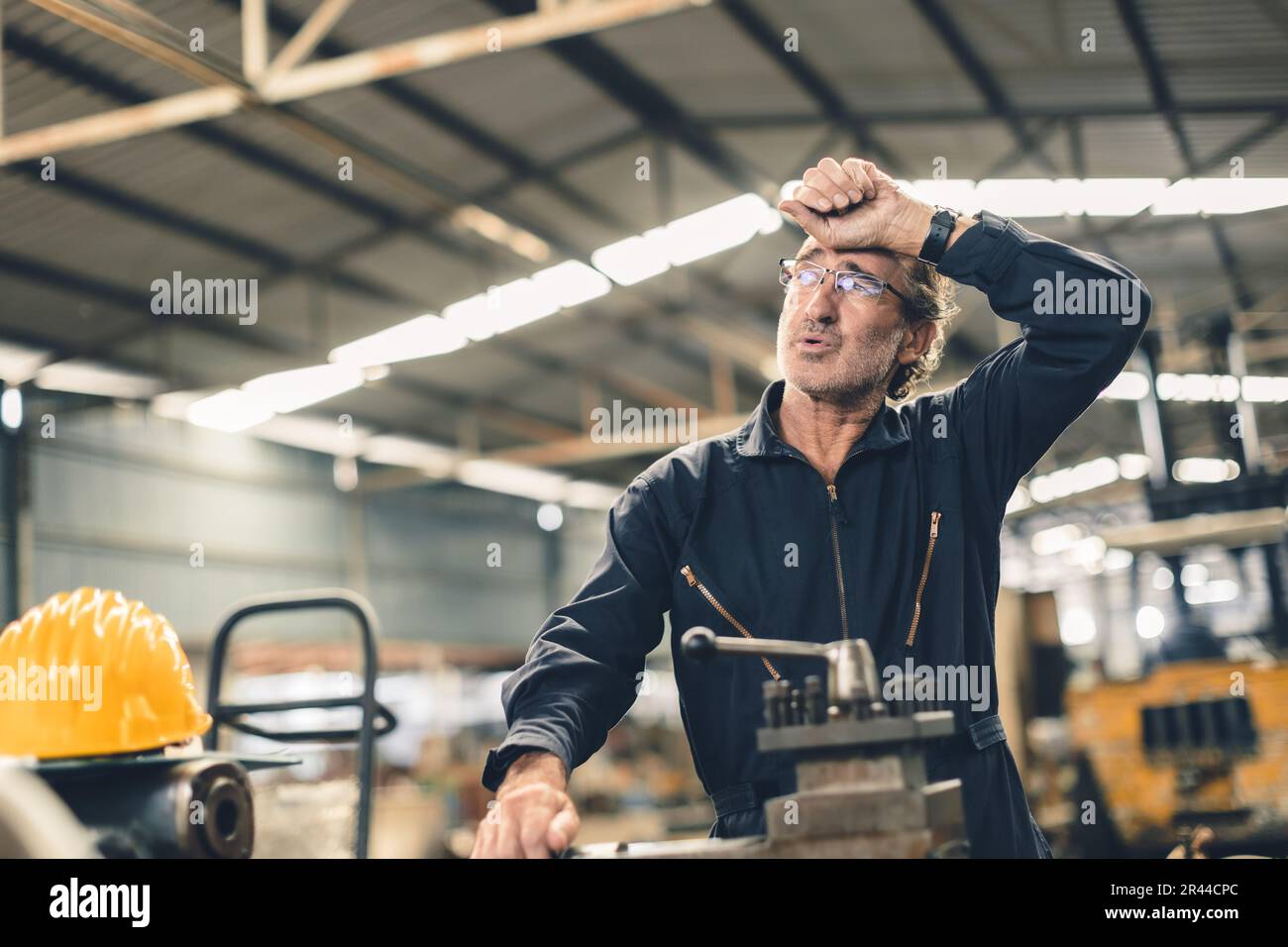 Tired sweat senior adult engineer worker hard work fatigue male staff in metal factory hot weather Stock Photo