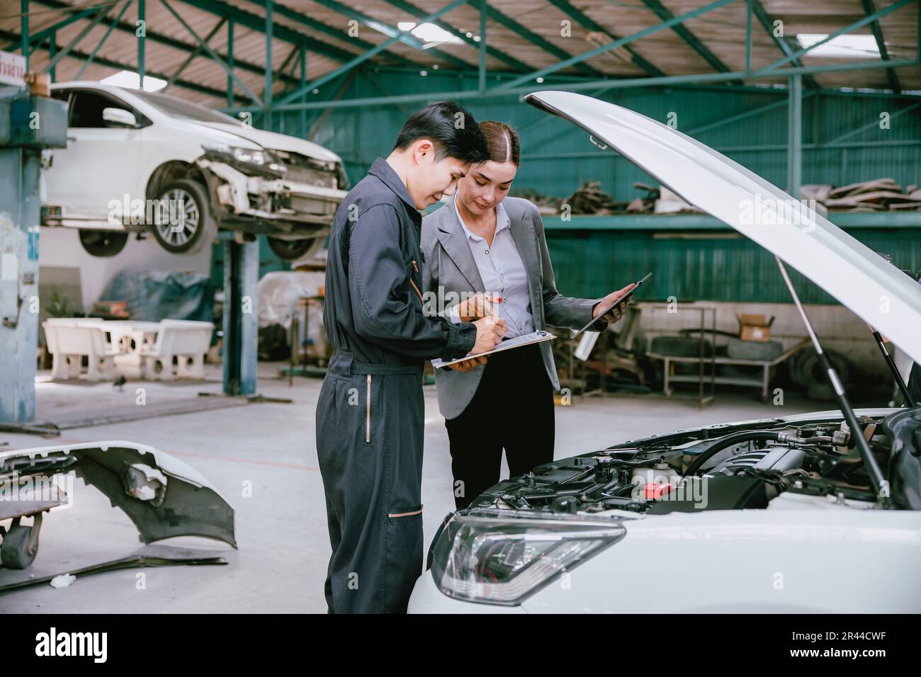 People working estimate repair cost in auto shop. Garage business owner car insurance claim team for help service fix repair broken car. Stock Photo