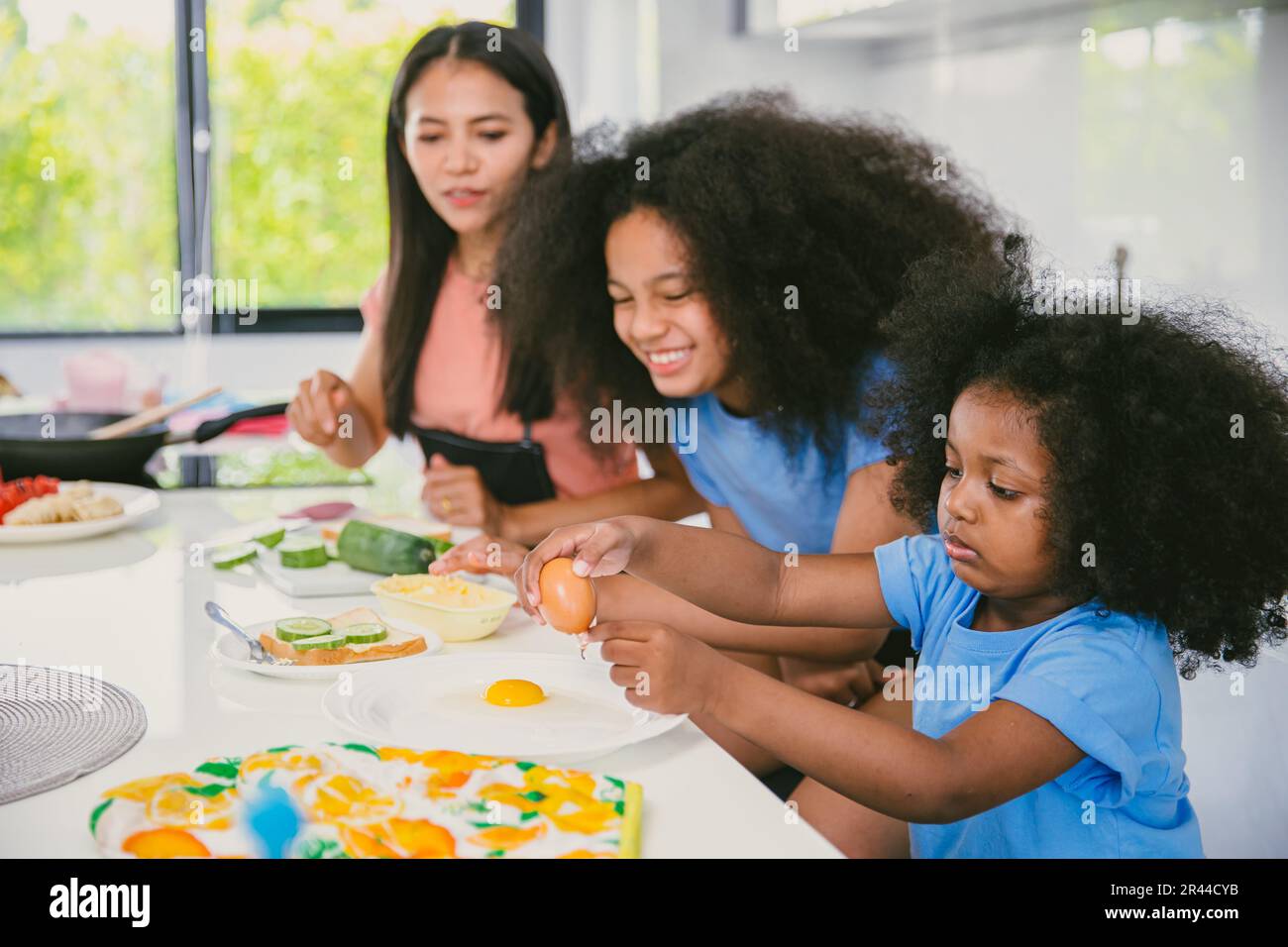 Children playing learning practise cooking food with mother at home kitchen happy funny holiday activity Stock Photo