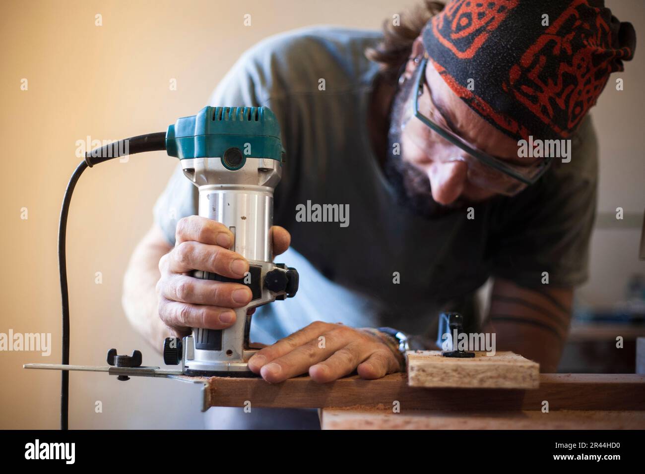 Intricate woodworking at its best as a skilled artisan uses a router to shape and mold the wood with meticulous precision. Stock Photo