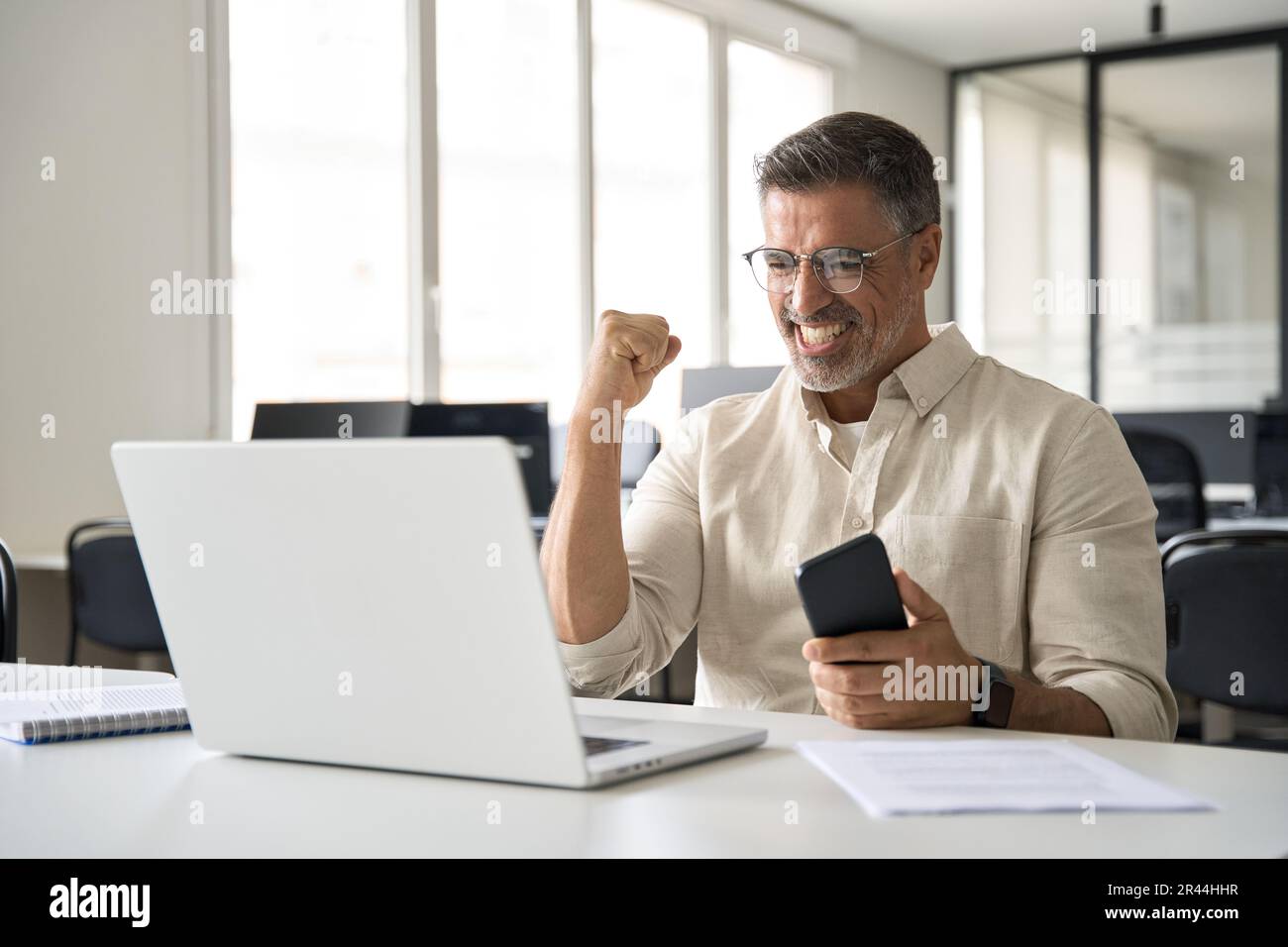 Middle aged man reading great news on smartphone celebrating victory and success Stock Photo