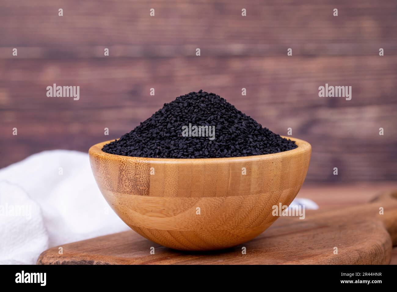 Black cumin or nigella sativa on wooden background. Black cumin seeds in wooden bowl. Kalonji, nigella, black cumin Stock Photo