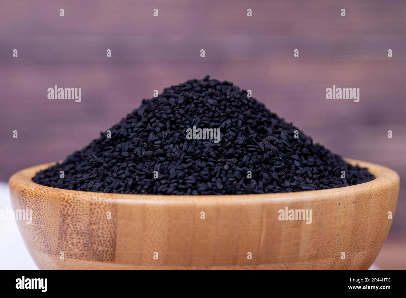 Black cumin or nigella sativa on wooden background. Black cumin seeds in wooden bowl. Kalonji, nigella, black cumin. Close up Stock Photo