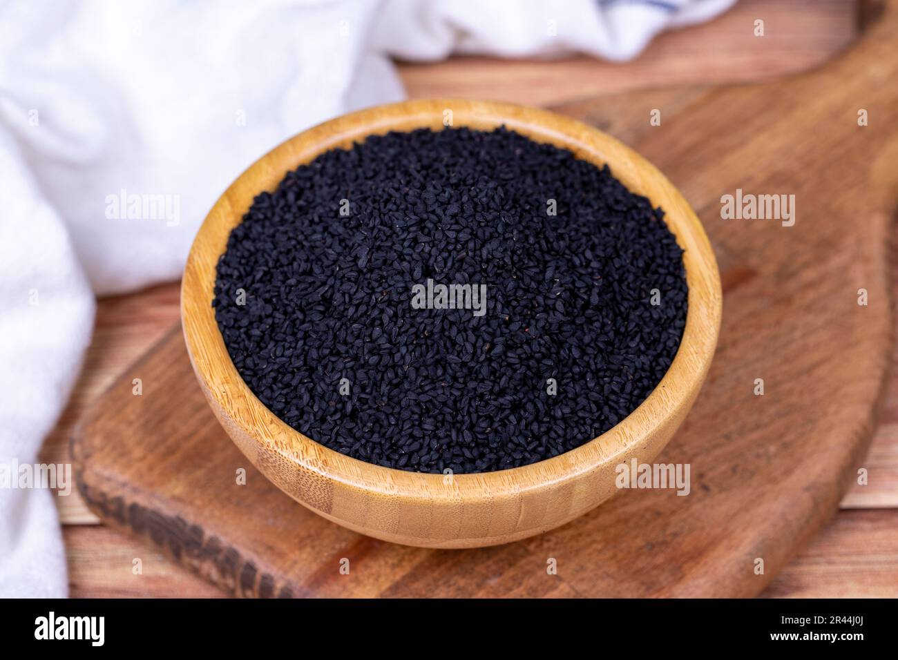 Black cumin or nigella sativa on wooden background. Black cumin seeds in wooden bowl. Kalonji, nigella, black cumin Stock Photo