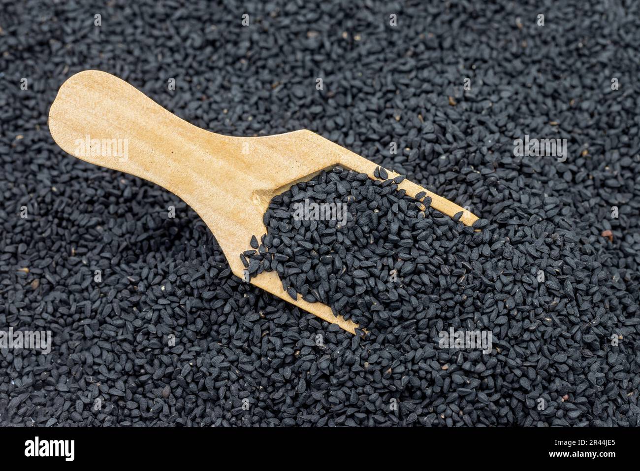 Pile of black cumin as background, spice or seasoning as background. Black cumin seeds in wooden spoon. Kalonji, nigella sativa, black cumin Stock Photo