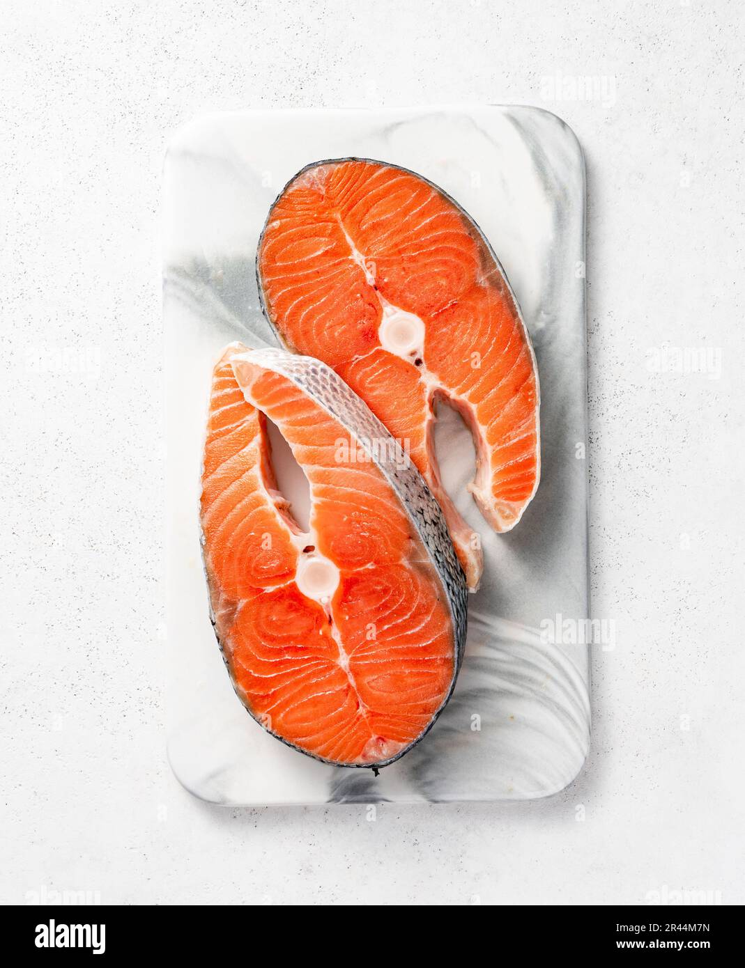Fresh raw salmon steaks on marble board. Top view of fish on white ...