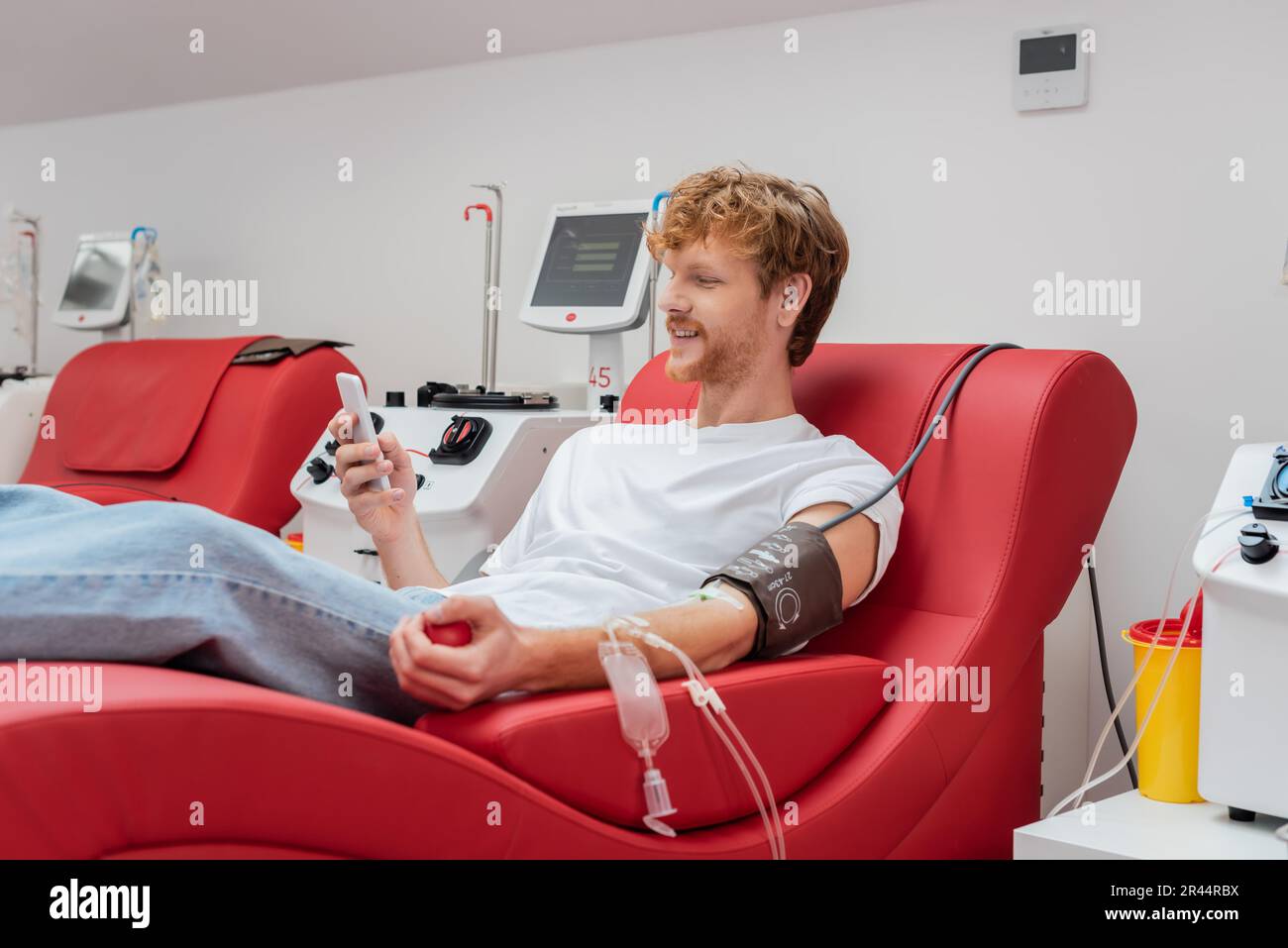 redhead and smiling man browsing internet on mobile phone in medical ...