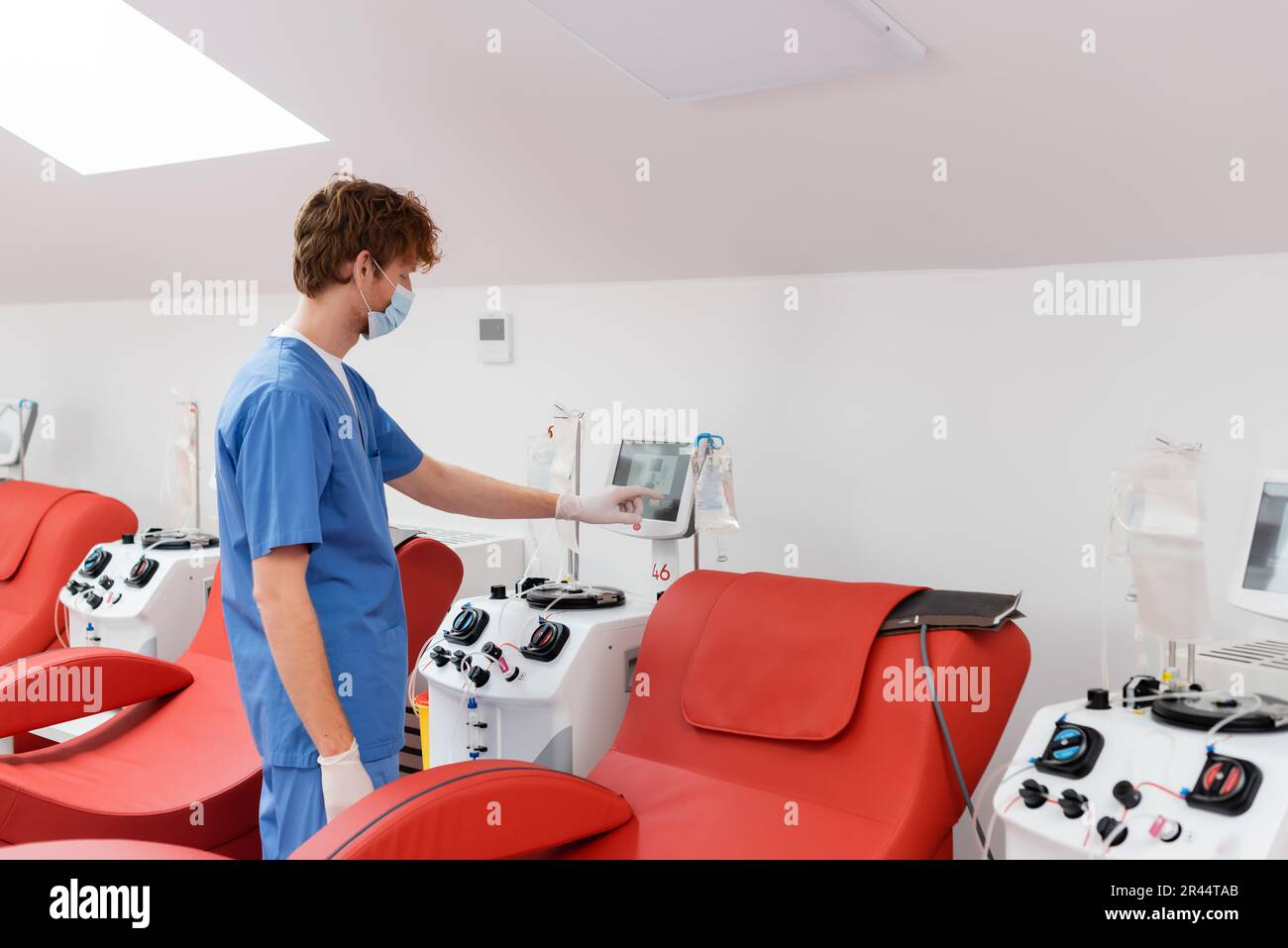 redhead doctor in medical mask, blue uniform and latex gloves operating ...