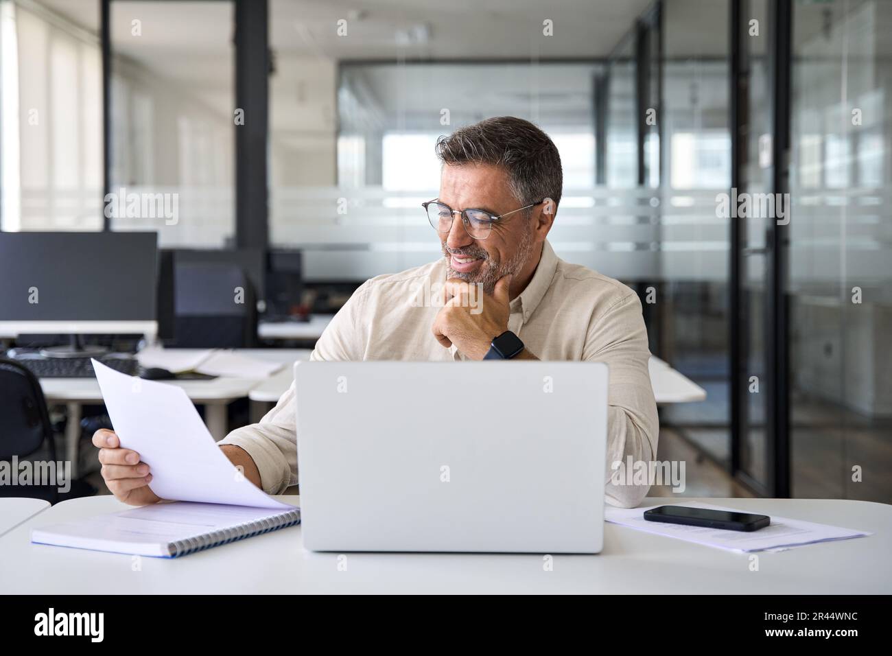 Focused Hispanic businessman doing paperwork in office with copy space. Stock Photo