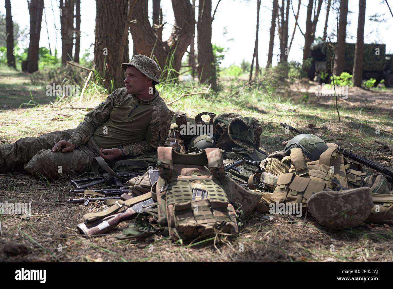 Kyiv Oblast, Ukraine. 25th May, 2023. An infantry soldier guards body armour and weapons as his comrades walk to the lunch truck, between training exercises. Soldiers of Ukraine's Armed Forces Regular Infantry recieve intensive medical training from volunteers of the Prytula Foundation. Trainers from the foundation learn from experts in NATO-style TCCC Western medical training. Soldiers at the large military base simulate frontline conditions, living in the forest and digging trenches over long periods of time. (Photo by Mihir Melwani/SOPA Images/Sipa USA) Credit: Sipa USA/Alamy Live News Stock Photo