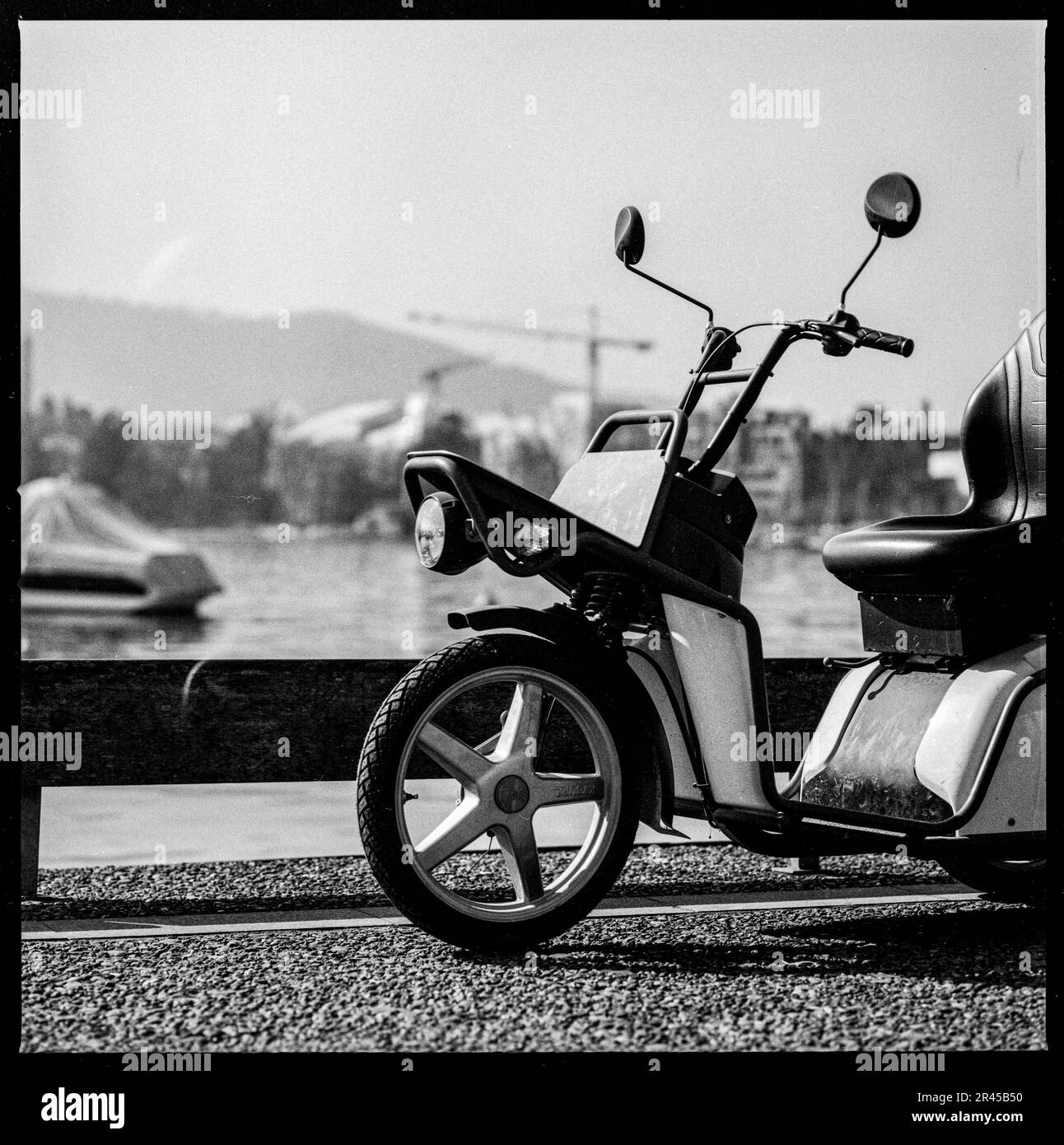 An beautiful black and white image of a motor scooter parked near a