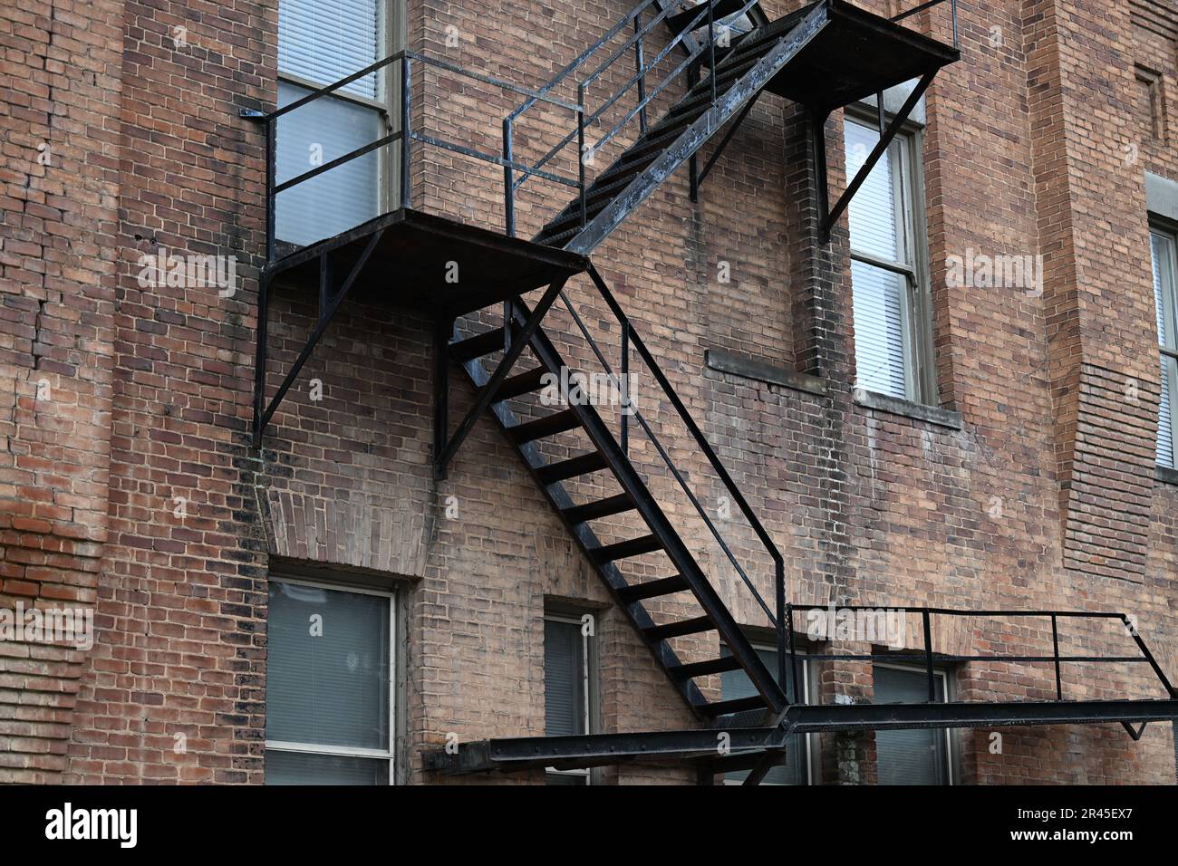 An exterior black fire escape staircase attached to the side of a red