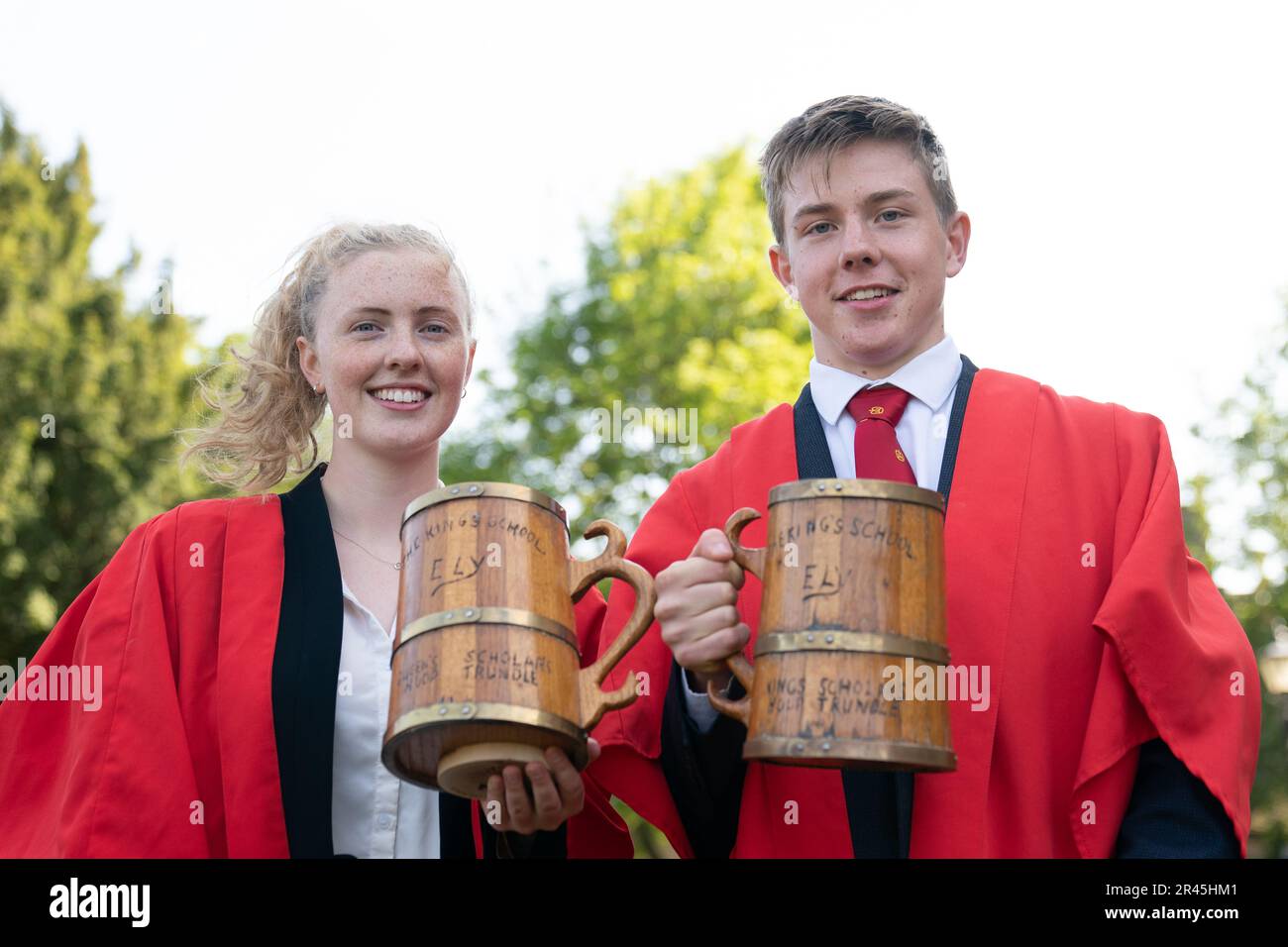 Nia Baird and Ben Collier celebrate with their respective tankards after winning the annual King's Ely Hoop Trundle on the east lawn at Ely Cathedral, to mark the re-founding of the school by King Henry VIII, in 1541. The course is a 75 yard dash to a post and back whilst bowling the hoop with a wooden stick. Picture date: Friday May 26, 2023. Stock Photo