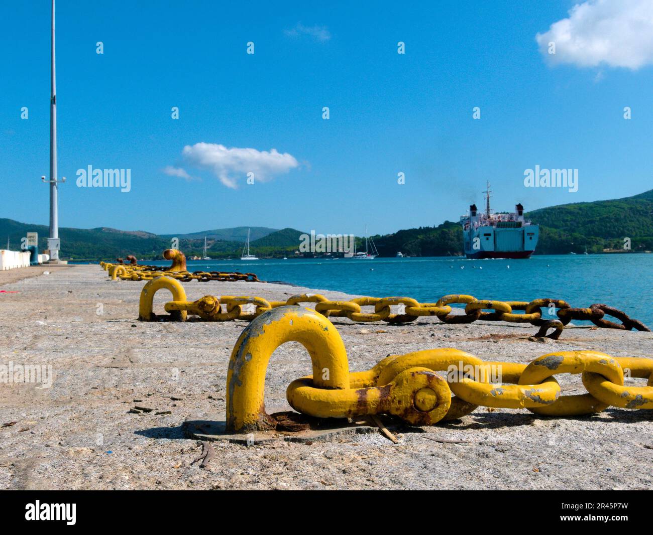 A vibrant yellow mooring and chain lay in the foreground of a scenic landscape Stock Photo