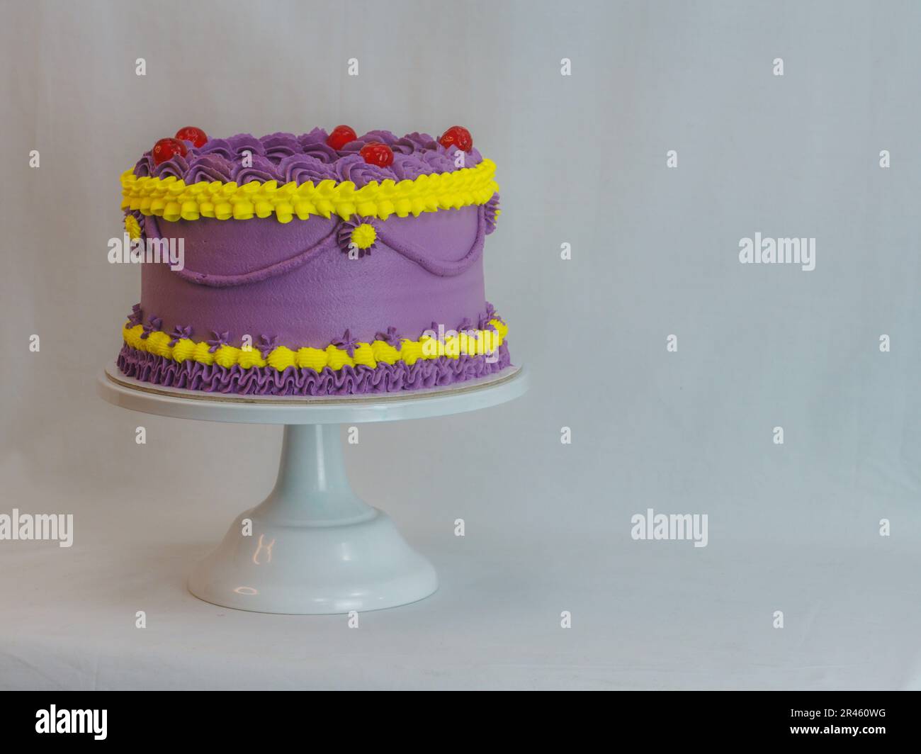frosted icing violet yellow classic cilyndrical cake with text messagge topping on studio white background. Romantic layered cupcake. Stock Photo