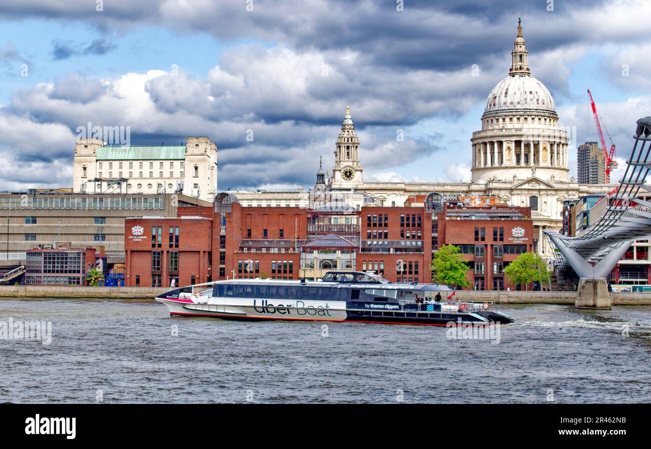 London River Thames looking towards St Pauls and City of London School with a passing Uber thames clipper boat Stock Photo