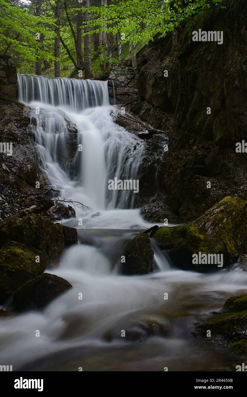 A majestic waterfall cascades over a towering array of large rocks in a ...