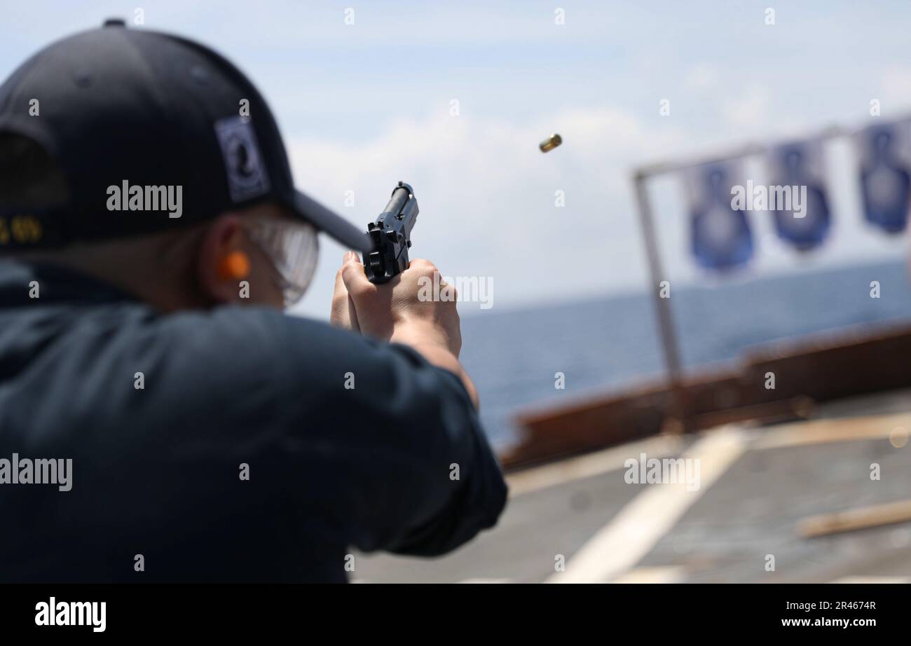 SOUTH CHINA SEA (March 27, 2023) – Boatswain’s Mate 3rd Class Juanpalo Capati, from Valejo, California, fires a 9 mm pistol during a live-fire exercise aboard the Arleigh Burke-class guided-missile destroyer USS Milius (DDG 69) while operating in the South China Sea, March 27. Milius is assigned to Commander, Task Force 71/Destroyer Squadron (DESRON) 15, the Navy’s largest forward-deployed DESRON and the U.S. 7th Fleet’s principal surface force. Stock Photo