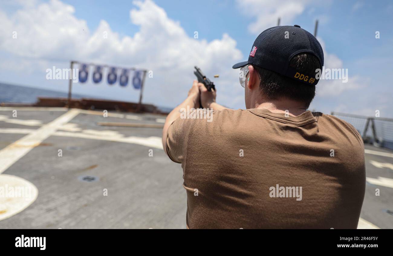 SOUTH CHINA SEA (March 27, 2023) – Operations Specialist 3rd Class David May, from Winchester, Virginia, fires a 9 mm pistol during a live-fire exercise aboard the Arleigh Burke-class guided-missile destroyer USS Milius (DDG 69) while operating in the South China Sea, March 27. Milius is assigned to Commander, Task Force 71/Destroyer Squadron (DESRON) 15, the Navy’s largest forward-deployed DESRON and the U.S. 7th Fleet’s principal surface force. Stock Photo