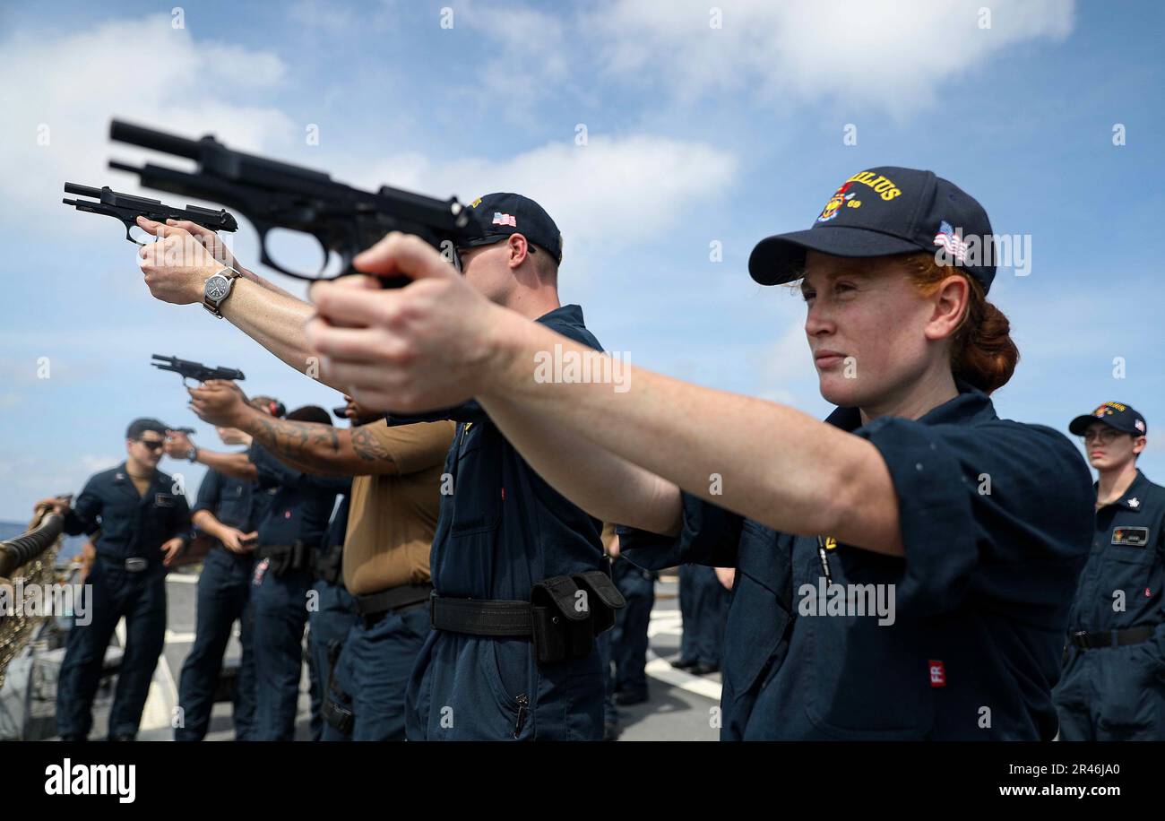 SOUTH CHINA SEA (March 27, 2023) – Lt. j.g. Kasey Castello, from Placentia, California, aims a 9 mm pistol during weapons familiarization training aboard the Arleigh Burke-class guided-missile destroyer USS Milius (DDG 69) while operating in the South China Sea, March 27. Milius is assigned to Commander, Task Force 71/Destroyer Squadron (DESRON) 15, the Navy’s largest forward-deployed DESRON and the U.S. 7th Fleet’s principal surface force. Stock Photo
