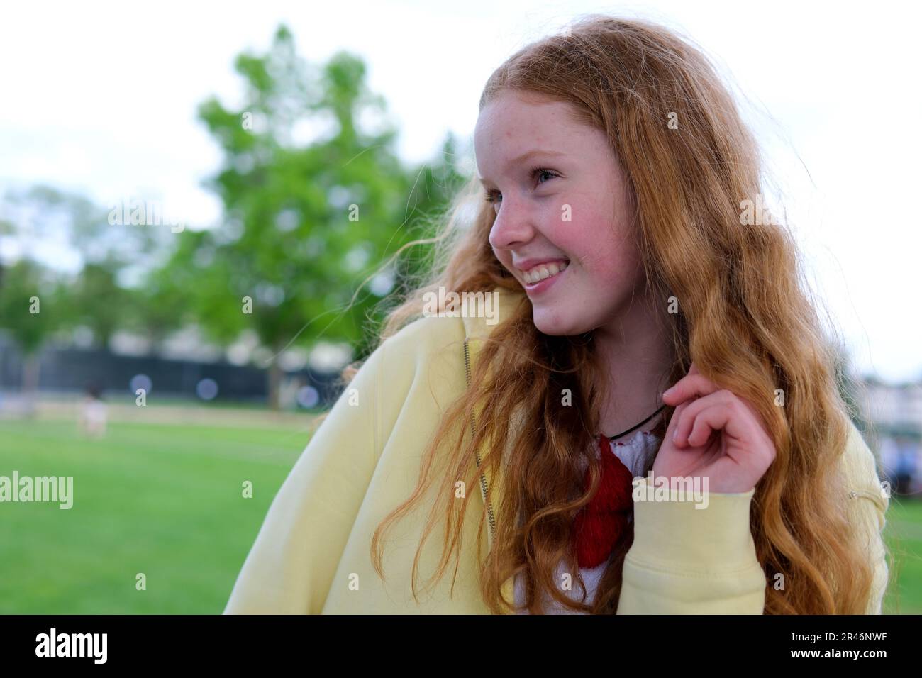 redhaired teenager girl against background of trees to be embarrassed