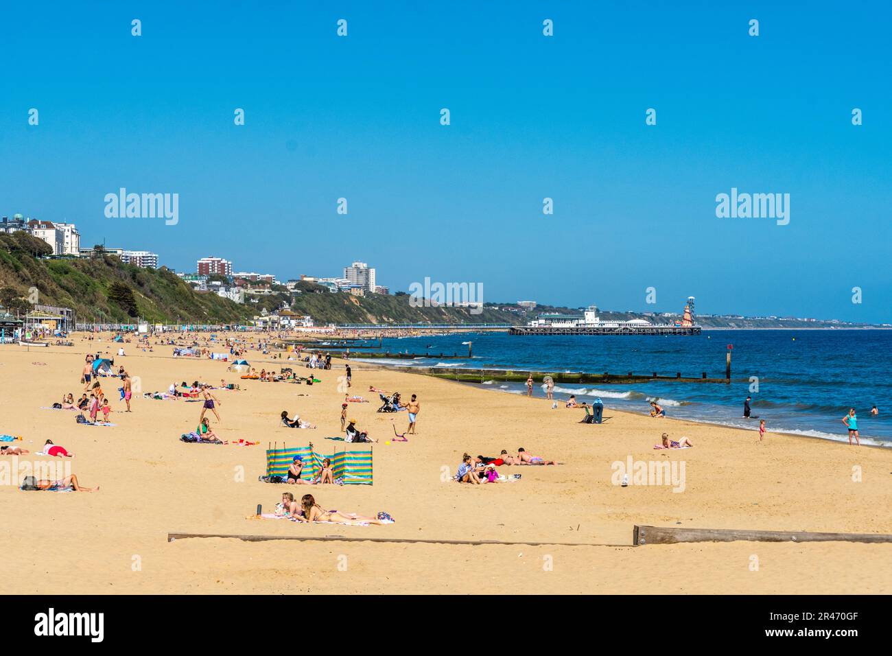 Bournemouth, UK - May 26th 2023: Sunbathers on Alum Chine Beach with Bournemouth Pier in the background. Stock Photo