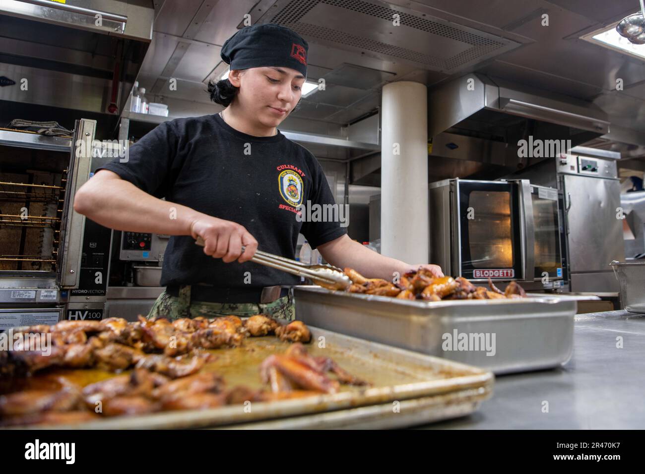 230324-N-MG537-3054 ATLANTIC OCEAN (March 24, 2023) Culinary Specialist Sarah Amaya prepares chicken for diner aboard the Arleigh Burke-class guided missile destroyer USS Bulkeley (DDG 84), March 23, 2023. Bulkeley routinely operates in the U.S. Naval Forces Europe and Africa area of operations, employed by U.S. Sixth Fleet to defend U.S., Allied and Partner interests. Stock Photo
