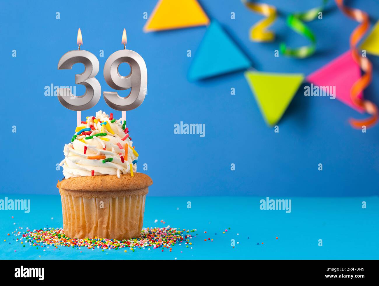 Cupcake with sparkling candle for 39th birthday or anniversary with big  number in white with yellow streamers on blue table with dark background  full Stock Photo - Alamy