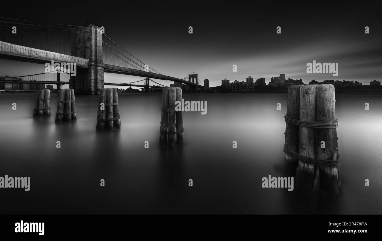 An aerial grayscale shot of the Brooklyn Bridge overlooking the East River. Stock Photo