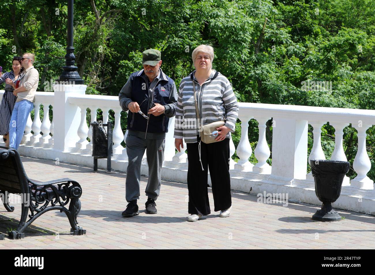 Russian pensioners (a man and a woman) walk along the Flower Garden Park at the Mineralnye Vody resort in the Russian Federation. Stock Photo