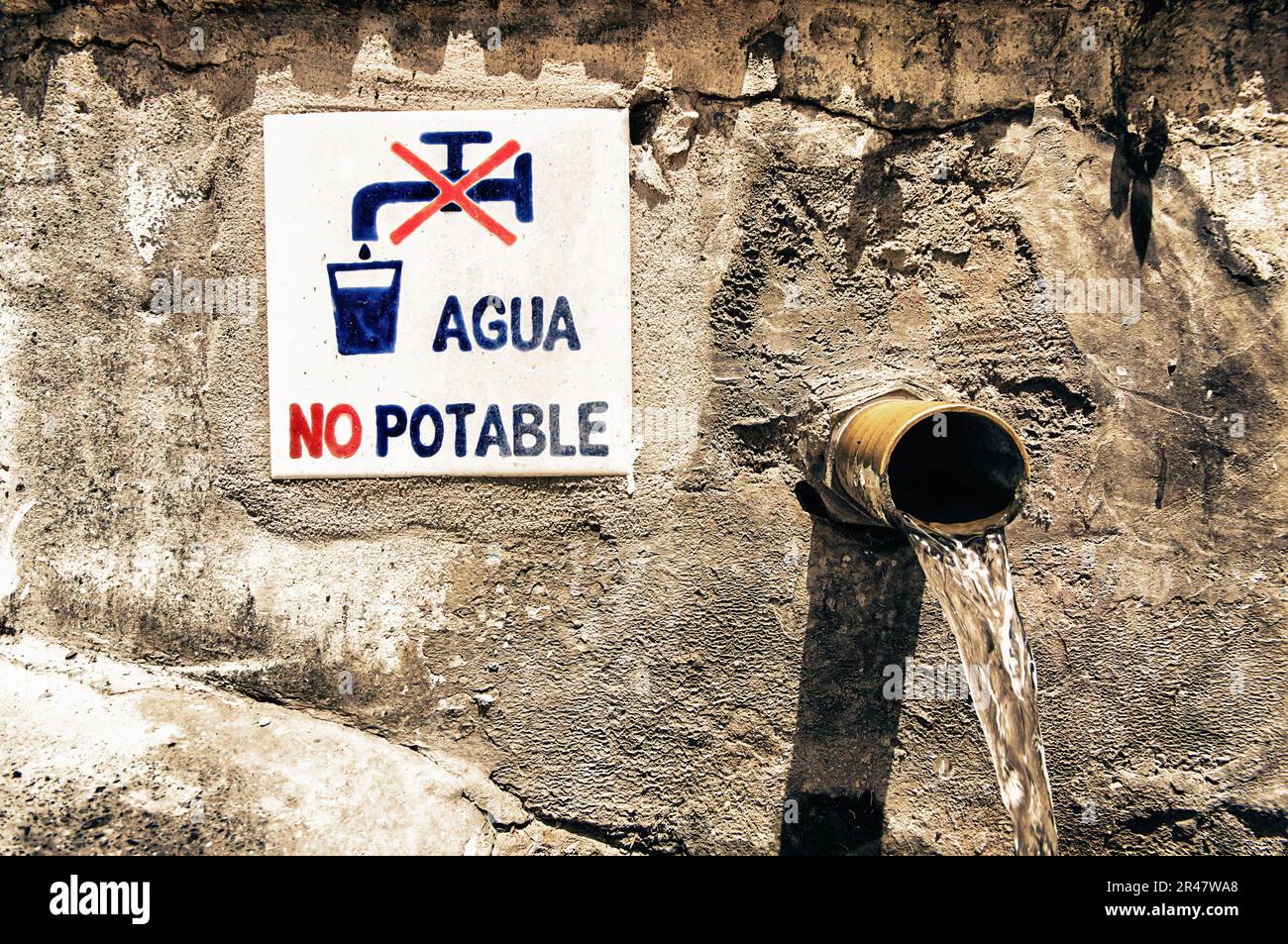 A sign located near a drain with a water spout pouring out of it, saying that the water is not potable Stock Photo