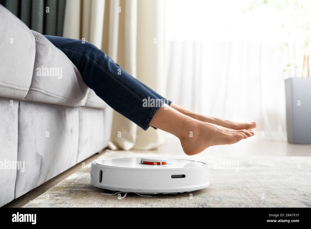 The robot vacuum cleaner does the cleaning in the living room. The girl