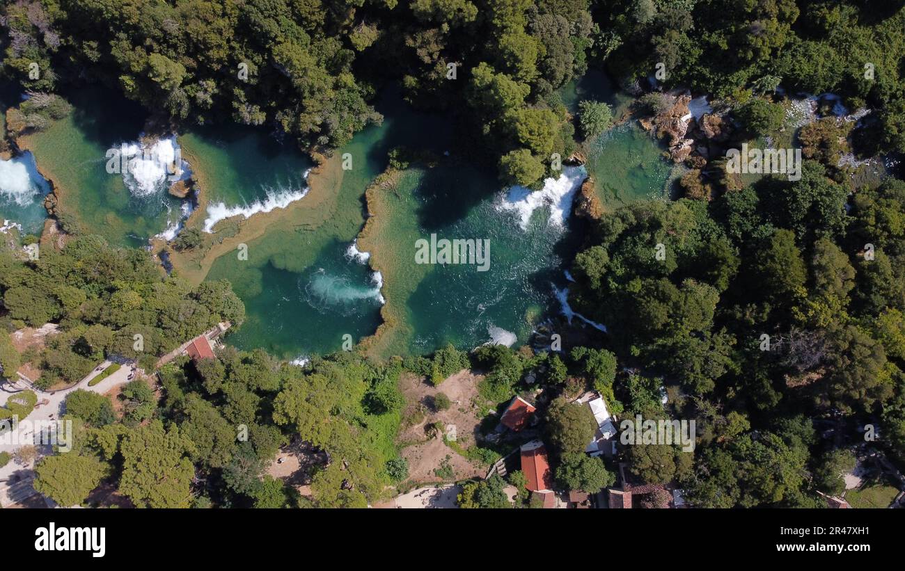 An aerial view of a cascading waterfall surrounded by lush green trees ...