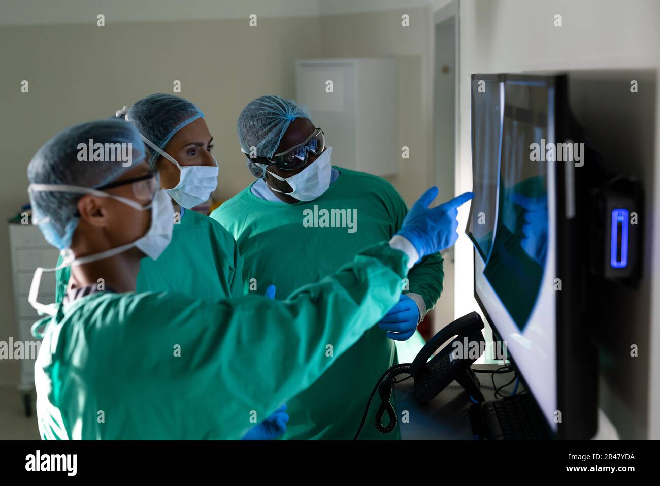 Diverse male and female surgeons looking at x-rays in operating theatre ...