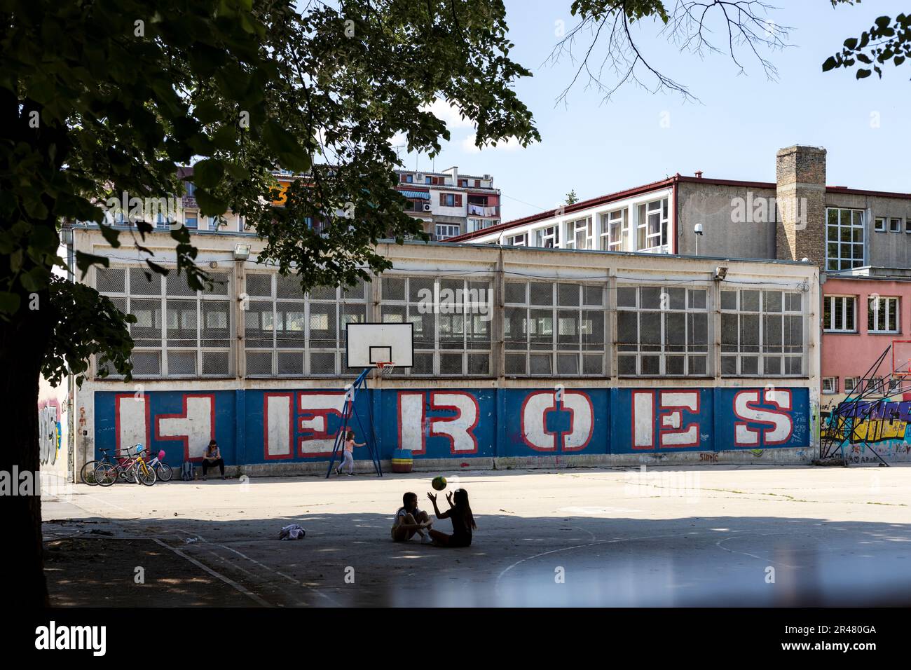 Belgrade, Serbia - 05-20-2023: Kids playing on a basketball court with graffiti that says heroes Stock Photo