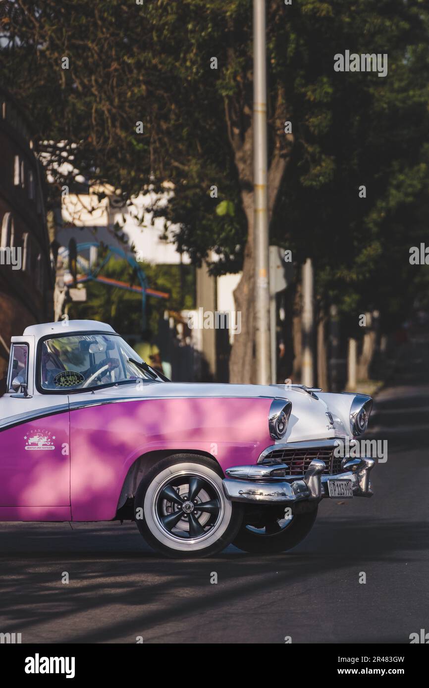 A vintage pink car parked on city street Stock Photo